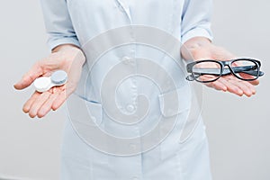 cropped view of optometrist in white coat holding eyeglasses and contact lens, Ð’Â 